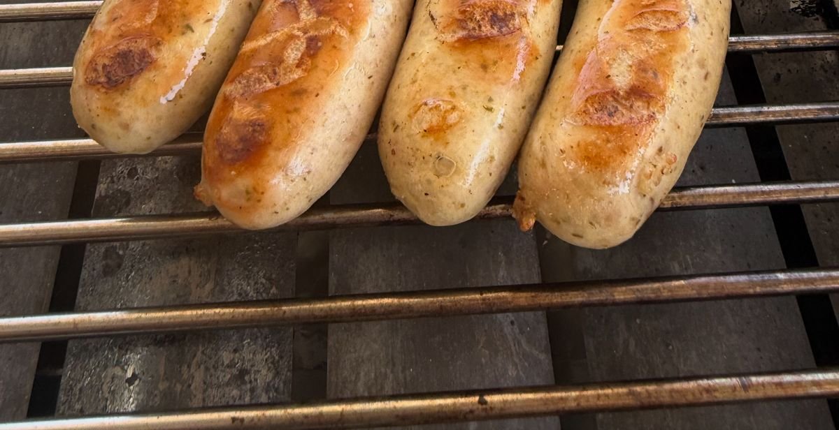 Cuatro Thüringer Bratwurst doradas sobre la parrilla del truck